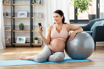 Image showing pregnant woman with phone and fitness ball at home