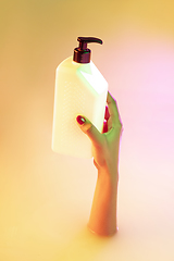 Image showing Close up female hand gesturing from the milk bath with soft glowing in neon light