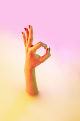 Image showing Close up female hand gesturing from the milk bath with soft glowing in neon light