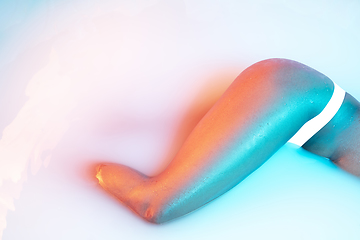 Image showing Close up female body in the milk bath with soft glowing in neon light