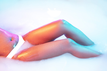 Image showing Close up female body in the milk bath with soft glowing in neon light