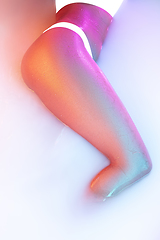 Image showing Close up female body in the milk bath with soft glowing in neon light