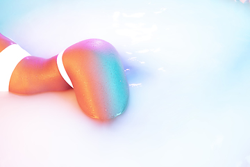Image showing Close up female body in the milk bath with soft glowing in neon light