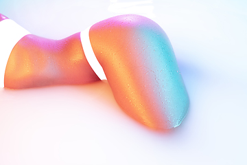 Image showing Close up female body in the milk bath with soft glowing in neon light