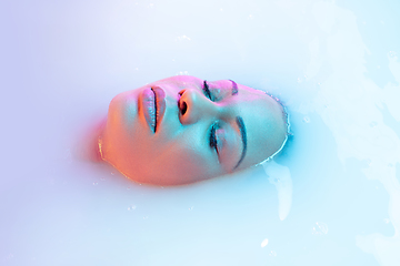 Image showing Close up female face in the milk bath with soft glowing in neon light