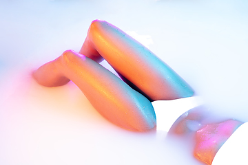 Image showing Close up female body in the milk bath with soft glowing in neon light