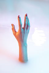 Image showing Close up female hand gesturing from the milk bath with soft glowing in neon light