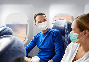 Image showing couple of passengers in masks travelling by plane