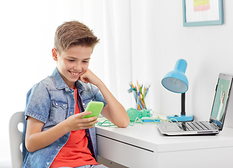 Image showing happy boy with smartphone and laptop at home