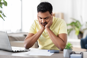 Image showing man with calculator and papers working at home