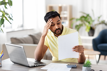 Image showing man with calculator and papers working at home