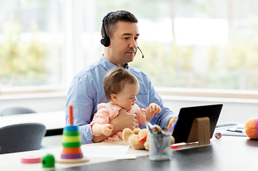 Image showing father in headset working at home office with baby