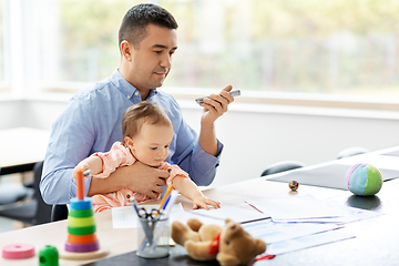 Image showing father with baby and phone working at home office