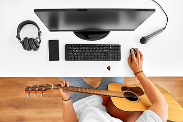 Image showing young man with computer and guitar at table