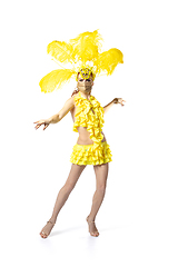 Image showing Beautiful young woman in carnival, stylish masquerade costume with feathers dancing on white studio background.