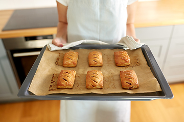 Image showing woman holding baking tray with pies at kitchen