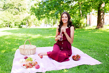 Image showing happy woman with picnic basket and drink at park