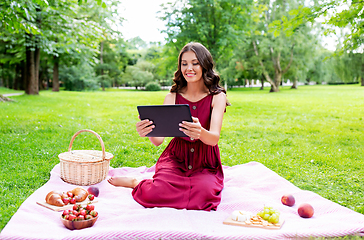 Image showing happy woman with tablet computer on picnic at park