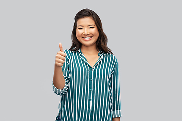 Image showing happy asian woman showing thumbs up over grey