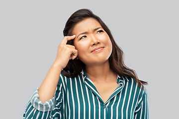 Image showing thinking asian woman over grey background