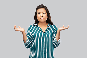 Image showing sad asian woman shrugging over grey background