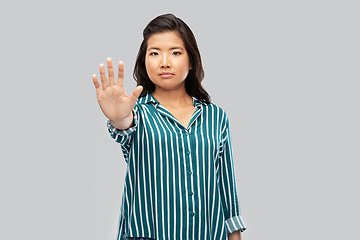 Image showing asian young woman showing stop gesture over grey