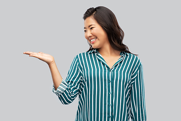 Image showing happy asian woman holding something on hand