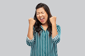 Image showing happy asian woman celebrating success over grey