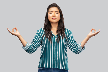 Image showing happy asian woman meditating over grey background