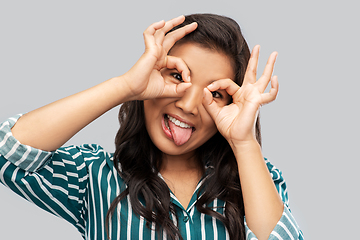 Image showing smiling asian woman looking through finger glasses