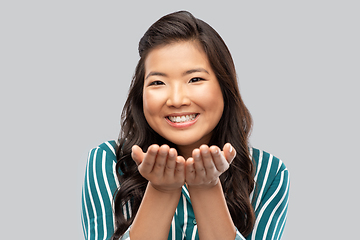 Image showing happy asian woman holding something on hands