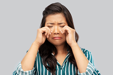 Image showing sad asian woman crying over grey background