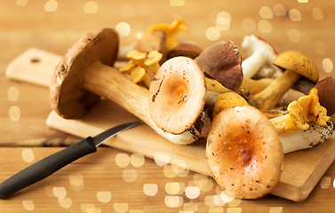 Image showing edible mushrooms on wooden cutting board and knife