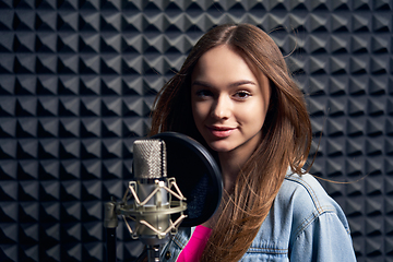 Image showing Teen girl in recording studio with mic over acoustic panel background