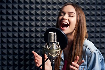 Image showing Teen girl in recording studio with mic over acoustic absorber panel background