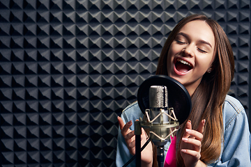 Image showing Teen girl in recording studio with mic over acoustic absorber panel background