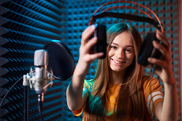 Image showing Girl in recording studio in headphones with mic over absorber panel background with closed eyes