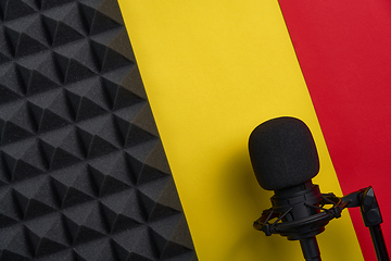 Image showing Flat lay of microphone and acoustic foam panel, over red and yellow background