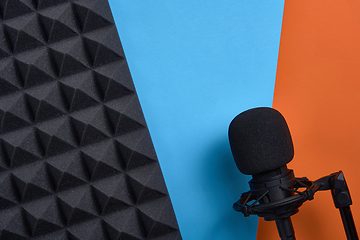 Image showing Flat lay of microphone and acoustic foam panel, over blue and orange background