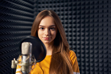 Image showing Teen girl in recording studio with mic over acoustic panel background