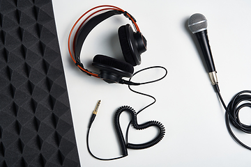 Image showing Microphone, headphones and heart shaped cable on on white background with acoustic foam panel on side