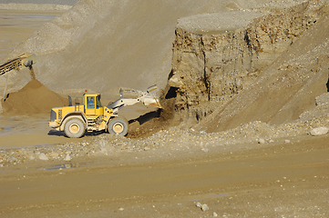 Image showing A yellow wheel loader is working in gravel pit