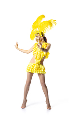 Image showing Beautiful young woman in carnival, stylish masquerade costume with feathers dancing on white studio background. Concept of holidays celebration, festive time, dance, party, having fun