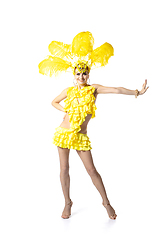 Image showing Beautiful young woman in carnival, stylish masquerade costume with feathers dancing on white studio background. Concept of holidays celebration, festive time, dance, party, having fun