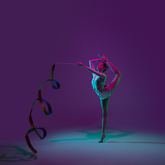 Image showing Young female athlete, rhythmic gymnastics artist on purple background with neon light. Beautiful girl practicing with equipment. Grace in performance.