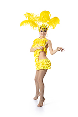 Image showing Beautiful young woman in carnival, stylish masquerade costume with feathers dancing on white studio background. Concept of holidays celebration, festive time, dance, party, having fun