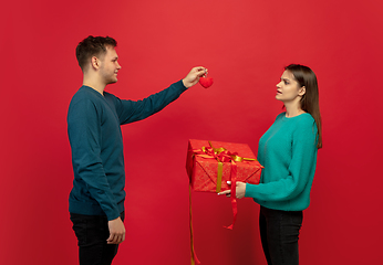 Image showing Beautiful couple in love on red studio background. Valentine\'s Day, love and emotions concept