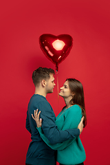 Image showing Beautiful couple in love on red studio background. Valentine\'s Day, love and emotions concept