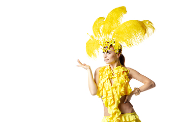 Image showing Beautiful young woman in carnival, stylish masquerade costume with feathers dancing on white studio background.