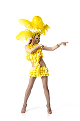 Image showing Beautiful young woman in carnival, stylish masquerade costume with feathers dancing on white studio background.